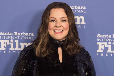 Actress Melissa McCarthy in a black dress poses at an event.